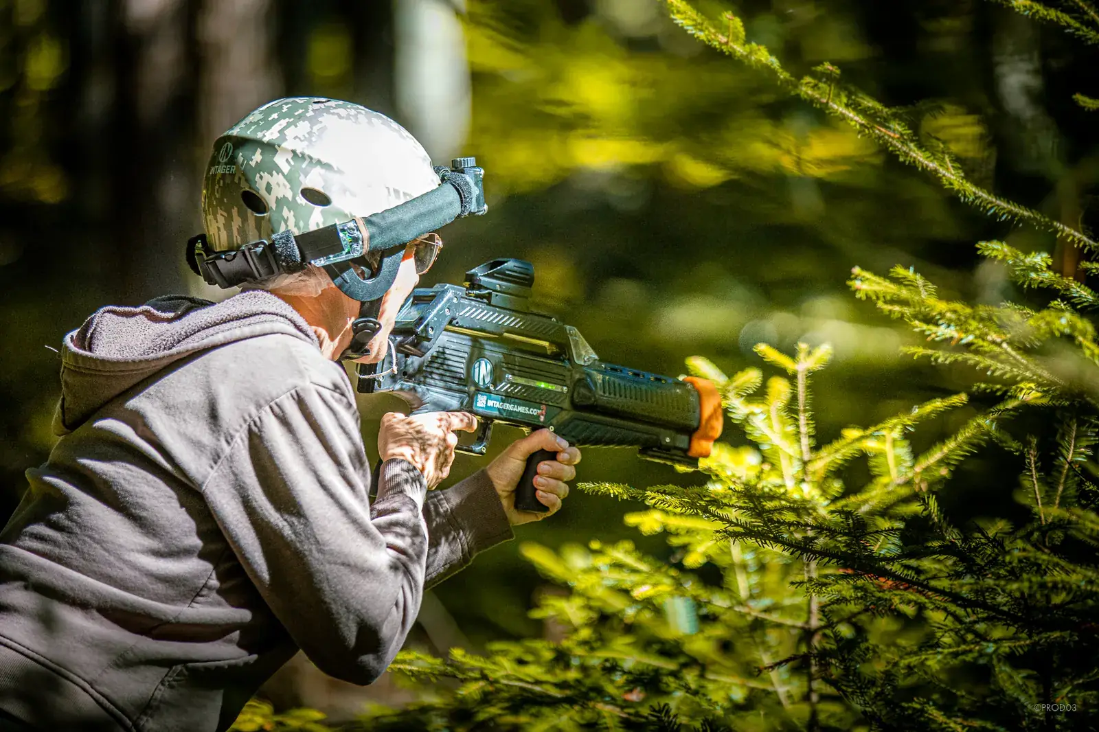 Joueur de laser game qui vise en forêt avec un lanceur et un casque